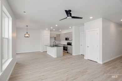Kitchen featuring open floor plan, stainless steel appliances, recessed lighting, dark countertops, and light wood-style floors