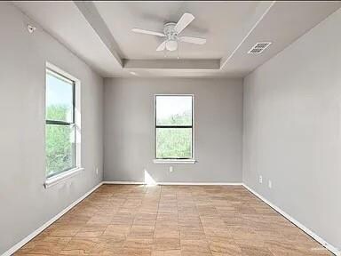 Spare room featuring plenty of natural light, a raised ceiling, and baseboards