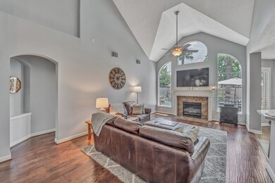 FAMILY ROOM - two story living space with cozy gas fireplace, built-in storage below the stairs and view of the backyard pool through large windows.