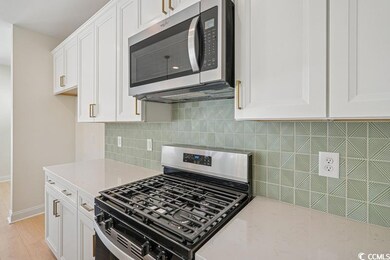 Kitchen featuring stainless steel appliances, white cabinetry, backsplash, and light wood-style floors