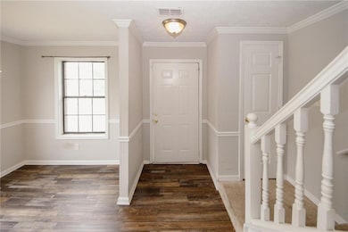Entryway with wood finished floors, ornamental molding, baseboards, and stairs