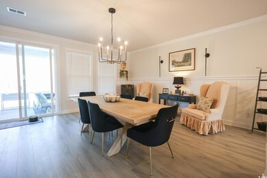 Dining room featuring visible vents, ornamental molding, wood finished floors, a decorative wall, and a chandelier