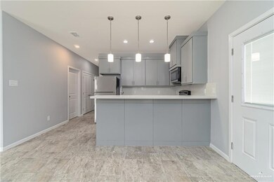 Kitchen with decorative light fixtures, refrigerator, gray cabinets, kitchen peninsula, and light tile floors