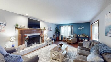 Living room featuring wood finished floors, a tile and wood gas fireplace, and recessed lighting and lots of natural light!