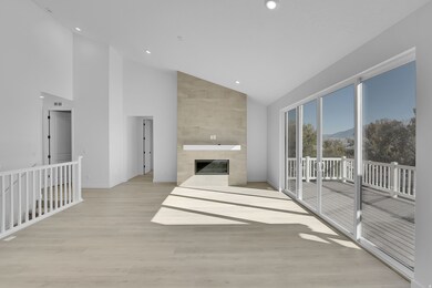 Unfurnished living room with high vaulted ceiling, light wood-style floors, a mountain view, a tiled fireplace, and recessed lighting