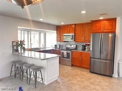 Kitchen featuring kitchen peninsula, a breakfast bar area, sink, light tile patterned flooring, and appliances with stainless steel finishes