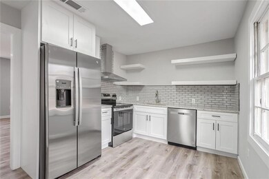 Kitchen with appliances with stainless steel finishes, open shelves, white cabinets, and decorative backsplash