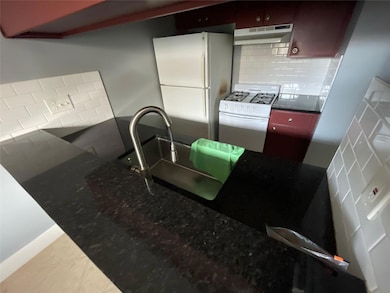 Kitchen featuring backsplash, white appliances, u