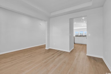 Unfurnished room featuring light wood-type flooring, a tray ceiling, and recessed lighting