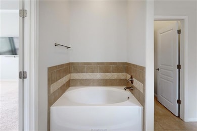 Full bathroom featuring a garden tub and tile patt