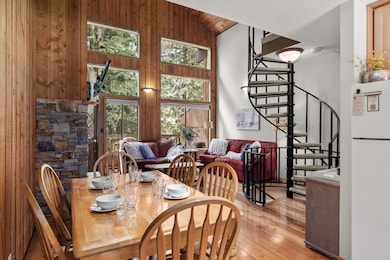 Dining room with light wood-type flooring, stairway, high vaulted ceiling, wood ceiling, and wood walls