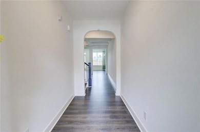 Corridor with arched walkways and dark wood finished floors