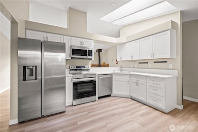 Sleek, modern kitchen design with new cabinetry, stainless appliances, quartz-style counters, and vaulted ceilings with skylights that flood the space with natural light.