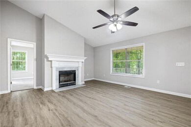 Unfurnished living room featuring lofted ceiling, wood finished floors, a high end fireplace, and ceiling fan
