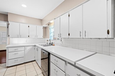 Kitchen with a sink, backsplash, white cabinets, l