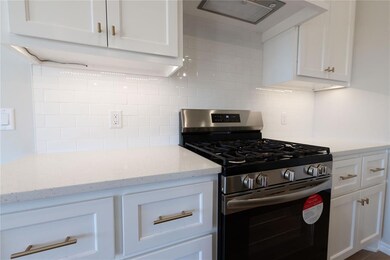 Kitchen featuring white cabinets, gas stove, and d