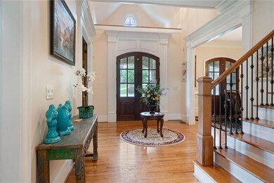 Foyer entrance featuring arched walkways, wood finished floors, stairs, crown molding, and a towering ceiling