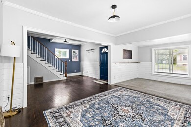 Foyer entrance with crown molding and dark wood-ty