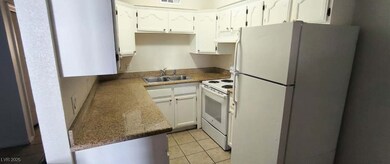 Kitchen with white appliances, light tile patterne