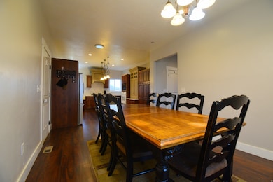 Dining area with a chandelier, dark wood-style flooring, and recessed lighting