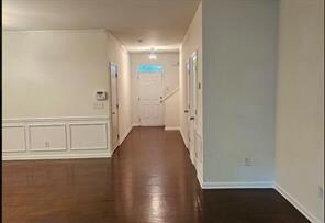Corridor featuring dark wood-type flooring and baseboards