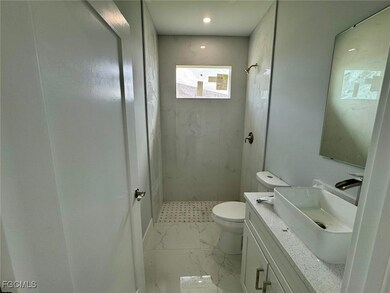 Bathroom featuring a shower stall, vanity, and marble look tiles