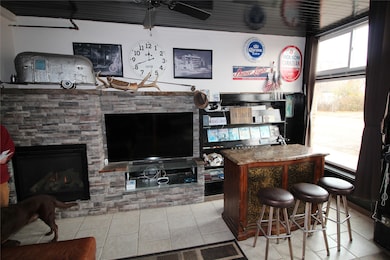 Bar area featuring light tile patterned flooring, a ceiling fan, a fireplace, and dark brown cabinetry