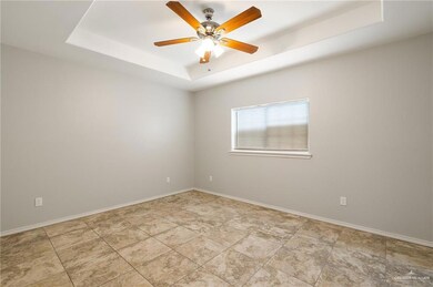 Empty room featuring ceiling fan and a tray ceiling