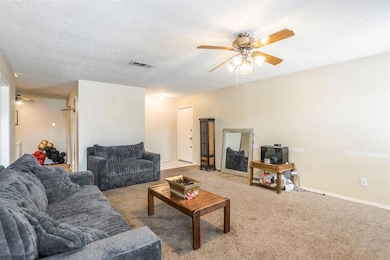 Living area with ceiling fan, carpet floors, and baseboards