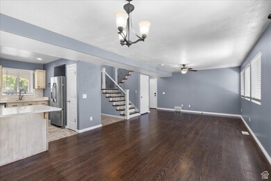 Unfurnished living room with ceiling fan, stairway, a chandelier, and light wood-type flooring