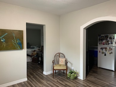 Hallway with arched walkways, dark wood-style floors, and a textured ceiling