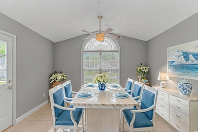 Dining area with light tile patterned floors, vaulted ceiling, ceiling fan, and healthy amount of natural light