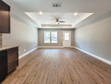 Unfurnished living room featuring a raised ceiling, light wood-type flooring, ceiling fan, and recessed lighting