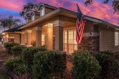 Property exterior at dusk featuring stone siding, covered porch, and stucco siding