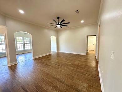 Unfurnished room featuring arched walkways, crown molding, a ceiling fan, dark wood finished floors, and recessed lighting