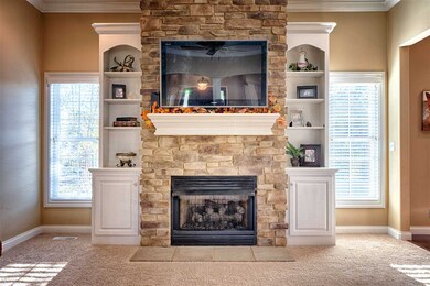 Gas fireplace surrounded by stone and built-in she