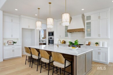 Kitchen with hanging light fixtures, custom range hood, white cabinetry, light wood-type flooring, and a breakfast bar area