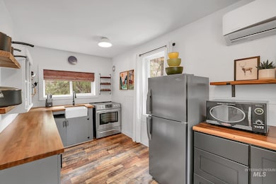 Kitchen with open shelves, butcher block countertops, appliances with stainless steel finishes, and gray cabinets