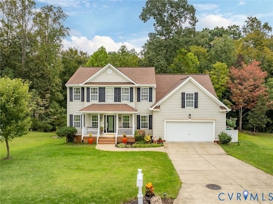 Colonial home featuring a front yard, covered porch, driveway, and roof with shingles