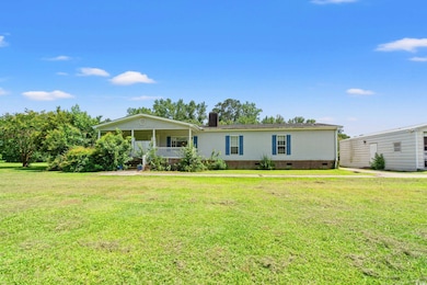 View of front facade featuring crawl space, covered porch, a chimney, and a front lawn