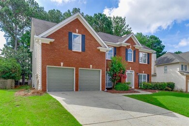 Colonial home featuring driveway, an attached garage, a front lawn, and brick siding