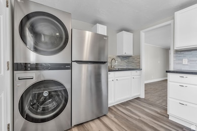 Laundry area featuring stacked washing machine and dryer and light wood finished floors