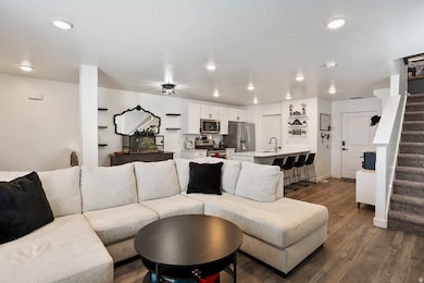 Living room with stairway, dark wood-type flooring, a textured ceiling, and recessed lighting