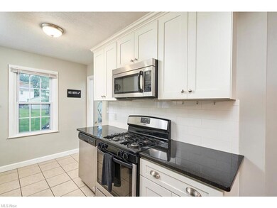 Kitchen featuring appliances with stainless steel finishes, white cabinetry, backsplash, and light tile floors