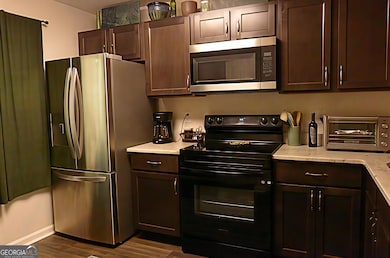 This recently updated kitchen boasts a spacious refrigerator, a functional electric stove, a convenient microwave, durable granite countertops, beautiful real wood cabinetry, and stylish, easy-to-maintain LVP (Luxury Vinyl Plank) flooring, creating a