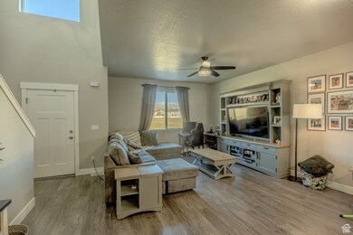 Living room featuring a textured ceiling, light wood-type flooring, and a ceiling fan