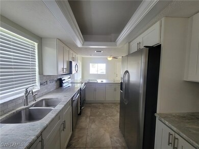 Kitchen featuring tasteful backsplash, stainless steel appliances, sink, crown molding, and a raised ceiling