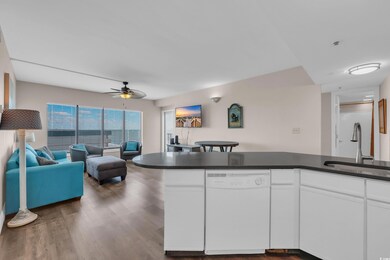 Kitchen featuring white dishwasher, open floor plan, dark countertops, ceiling fan, and white cabinetry