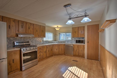 Kitchen includes stainless steel appliances, laminiate flooring and beautiful tiled backsplash.