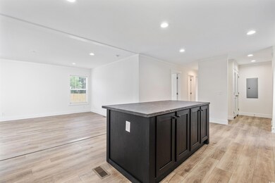Kitchen with dark countertops, crown molding, dark cabinets, a center island, and light wood-type flooring